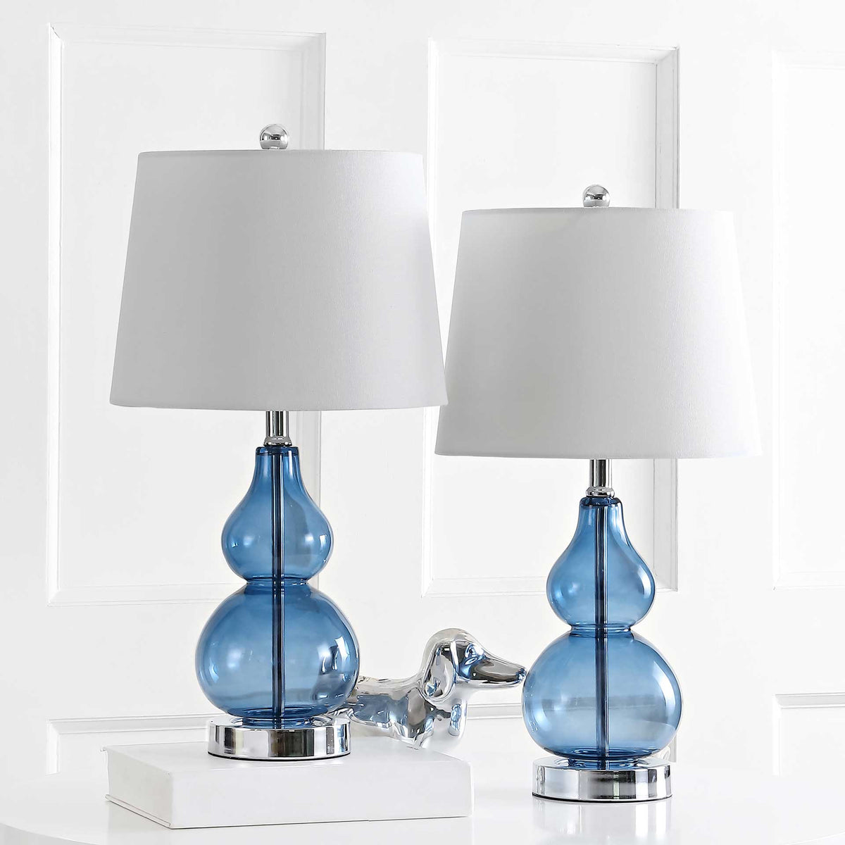 Matching blue glass lamps bring sculptural curves and polished chrome details to a bright room. || TBL4222B-SET2 || front_multi_room