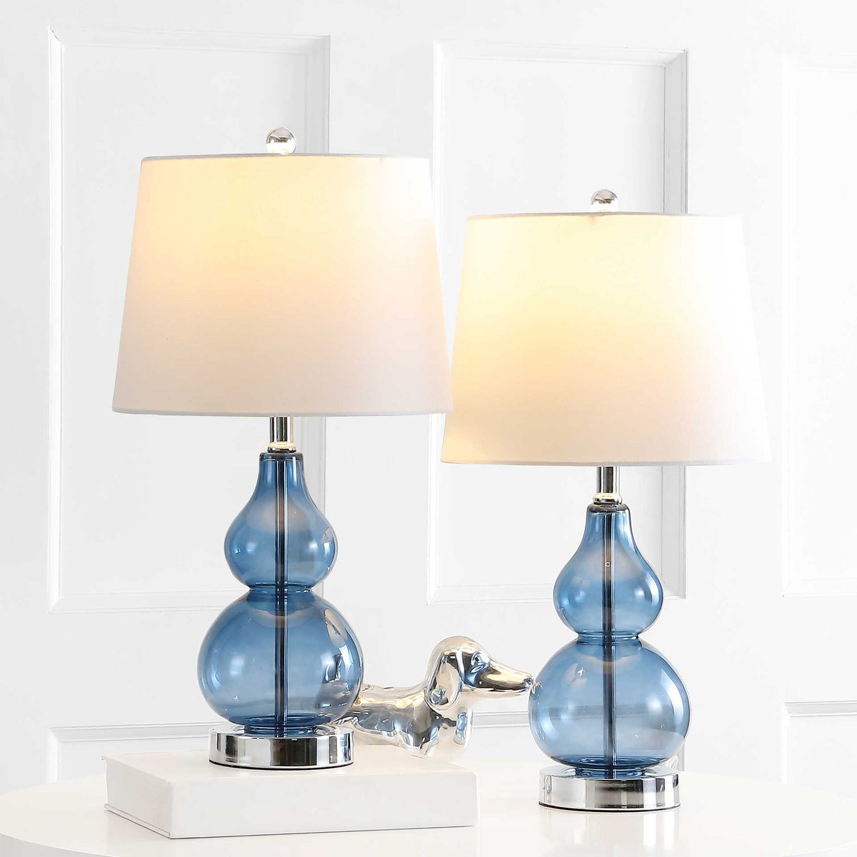 Two blue glass lamps cast a warm glow through white shades above gleaming chrome bases.