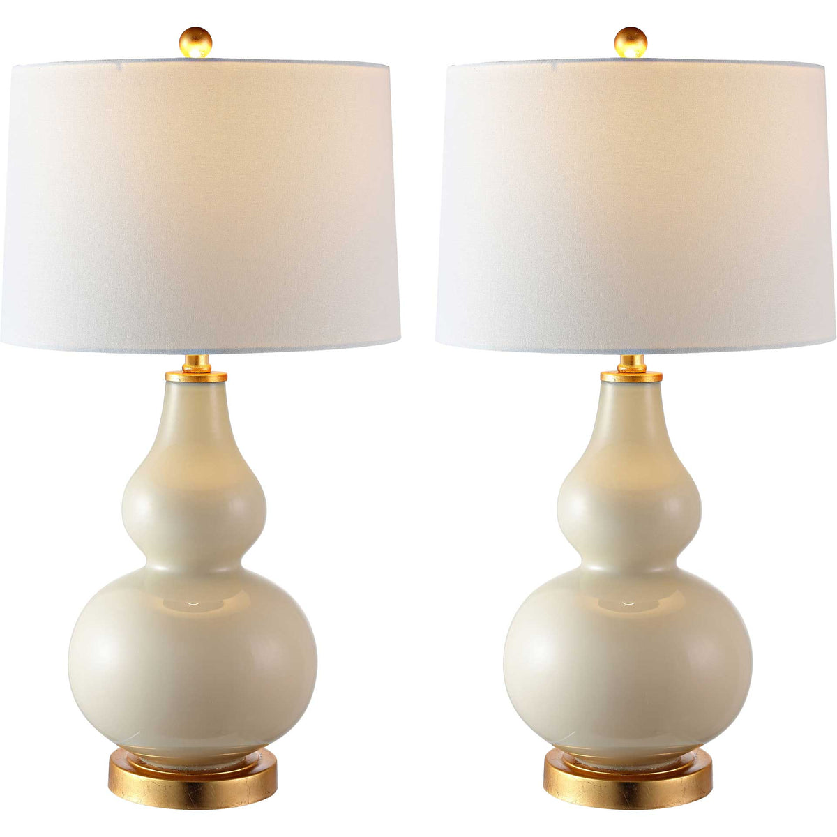 Two cream glass lamps cast a warm glow through their white shades above gleaming gold-tone bases.