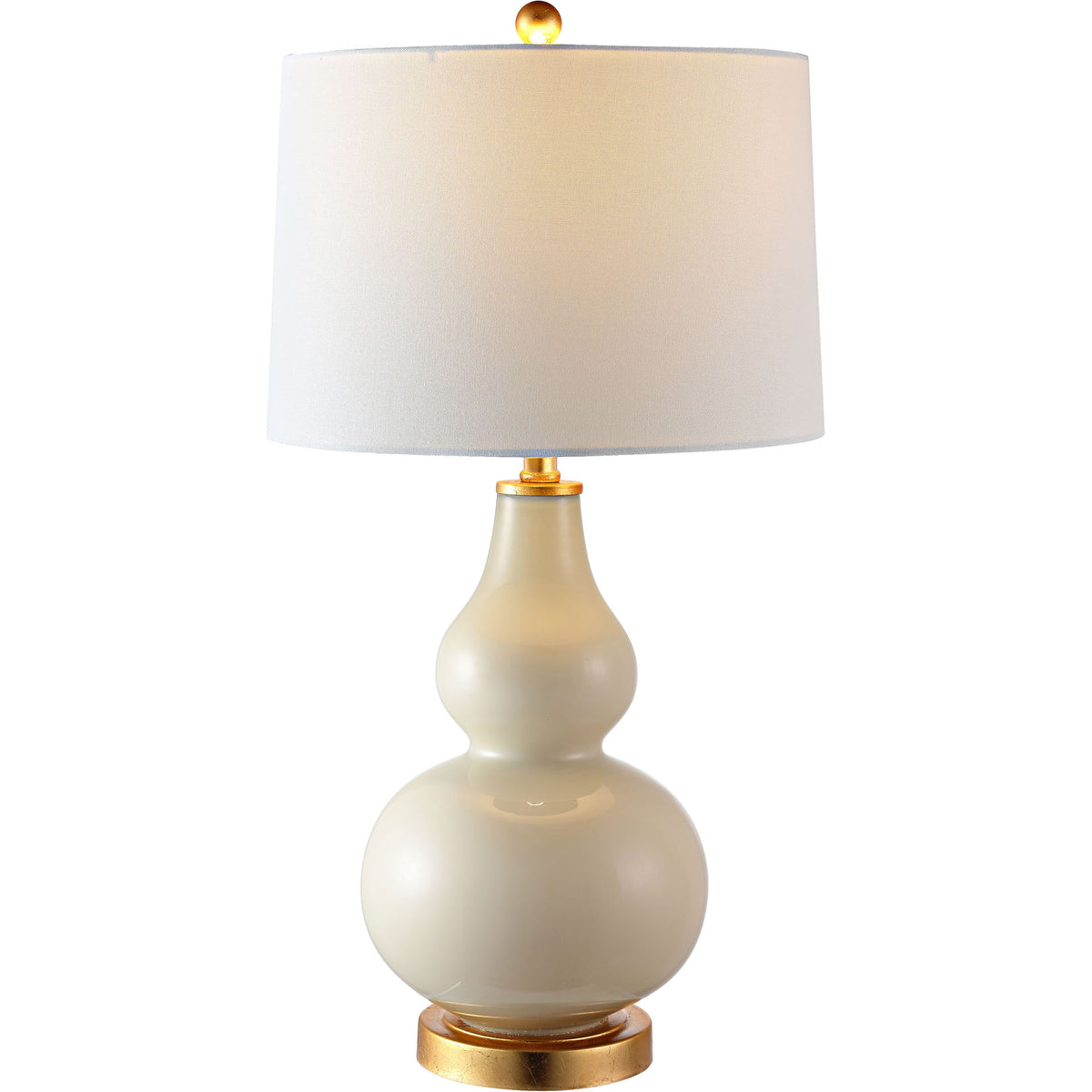 Warm light glows through a white fabric shade atop a curvy cream glass base with gold-tone accents.