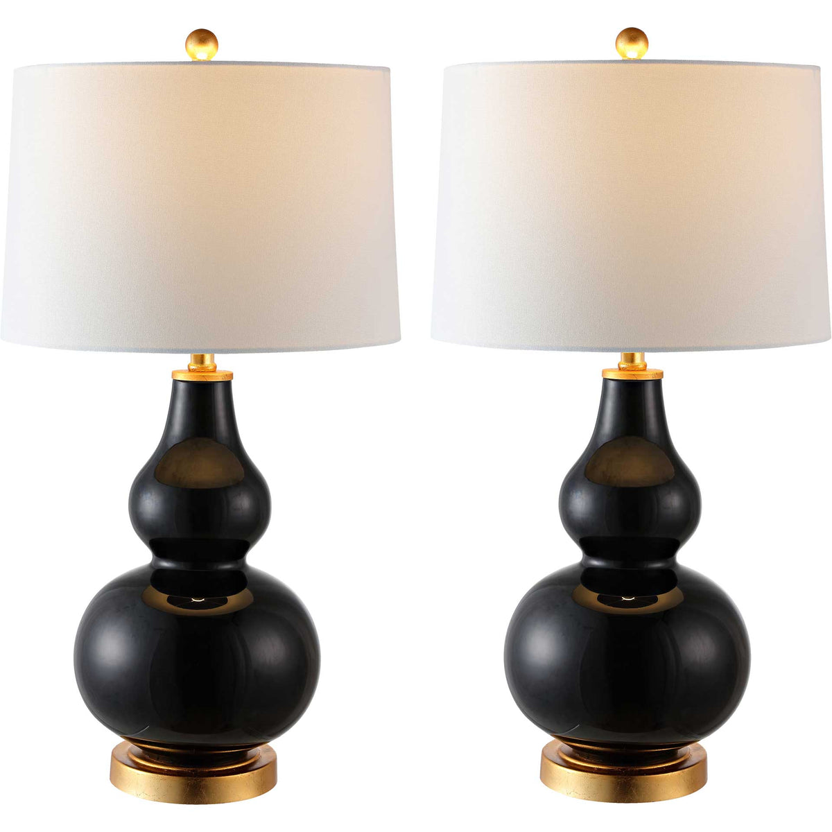 Matching black glass lamps glow beneath white fabric shades with gold-tone bases and finials.
