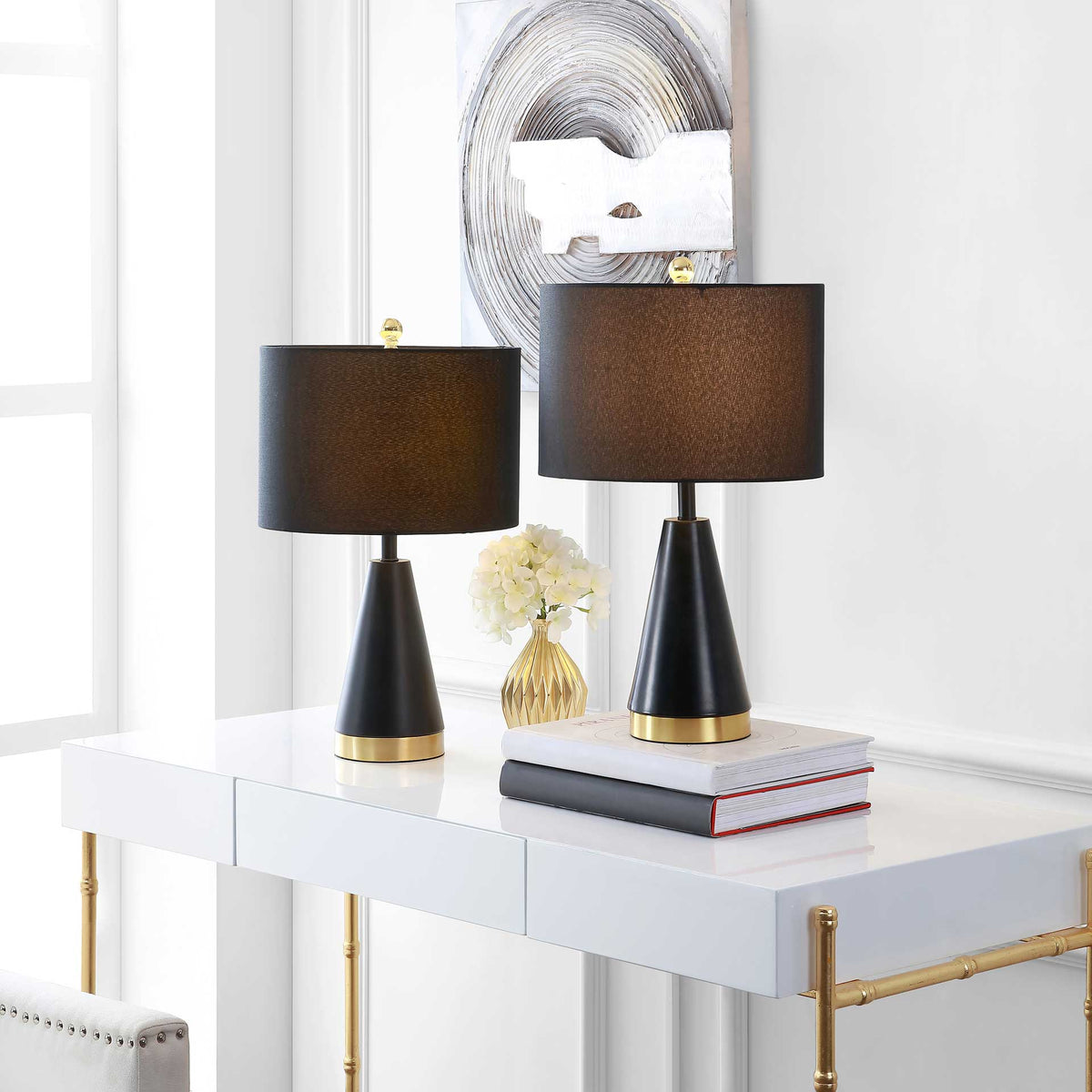 A pair of softly glowing black drum shades brings warm light to gold-trimmed bases