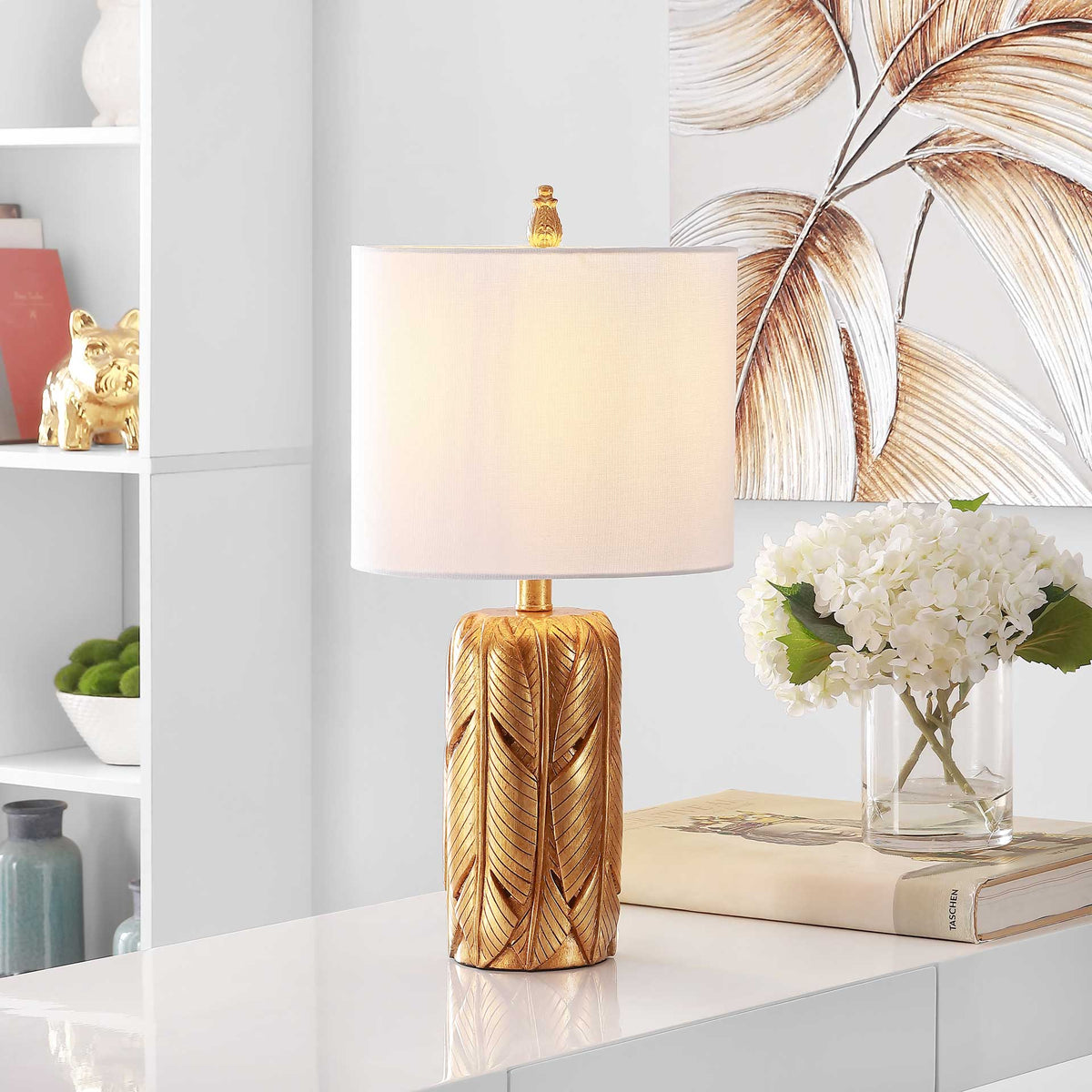 Warm light shines through the white drum shade above an intricately patterned gold base