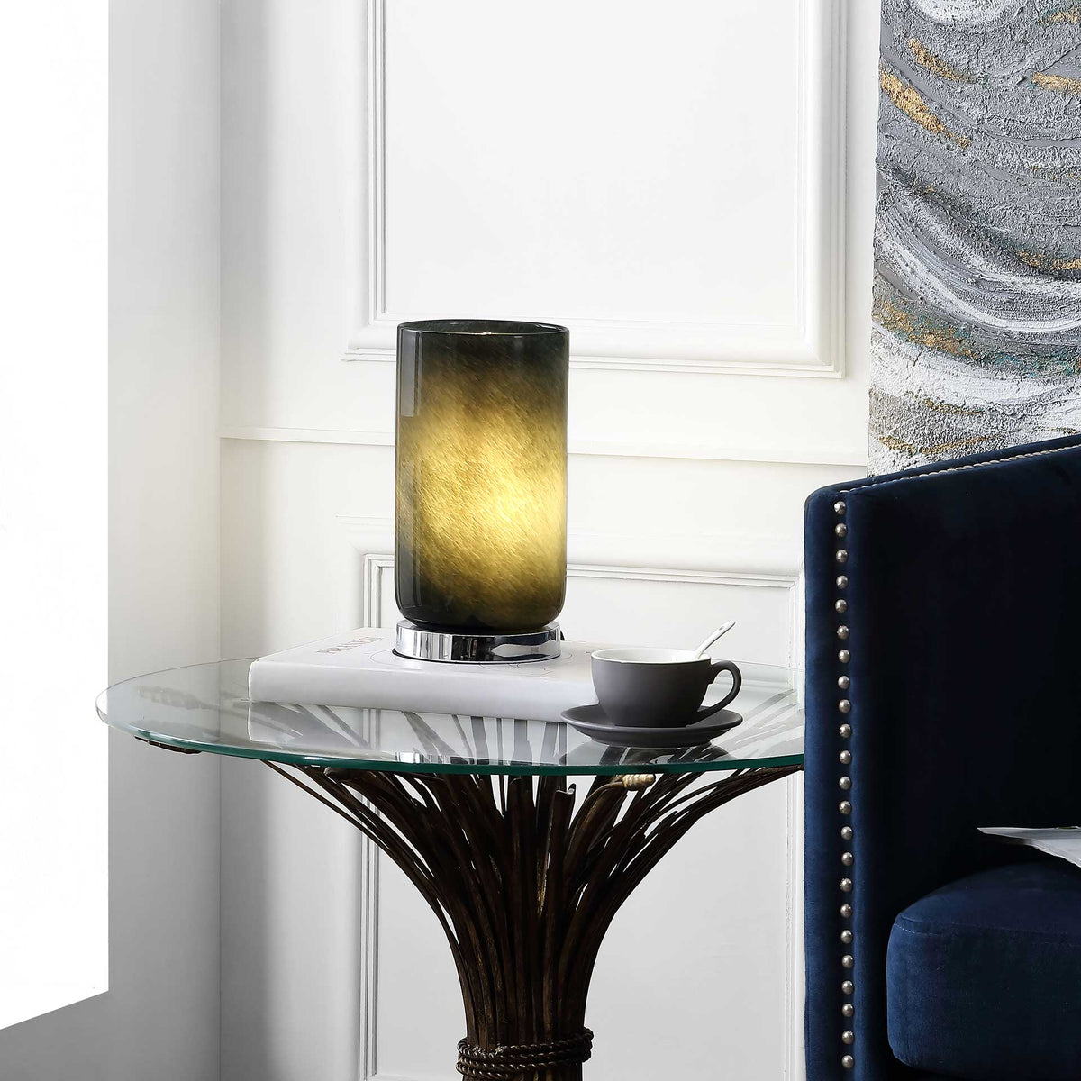 Soft golden light glows through the blue-gray glass shade, warming a living room seating area