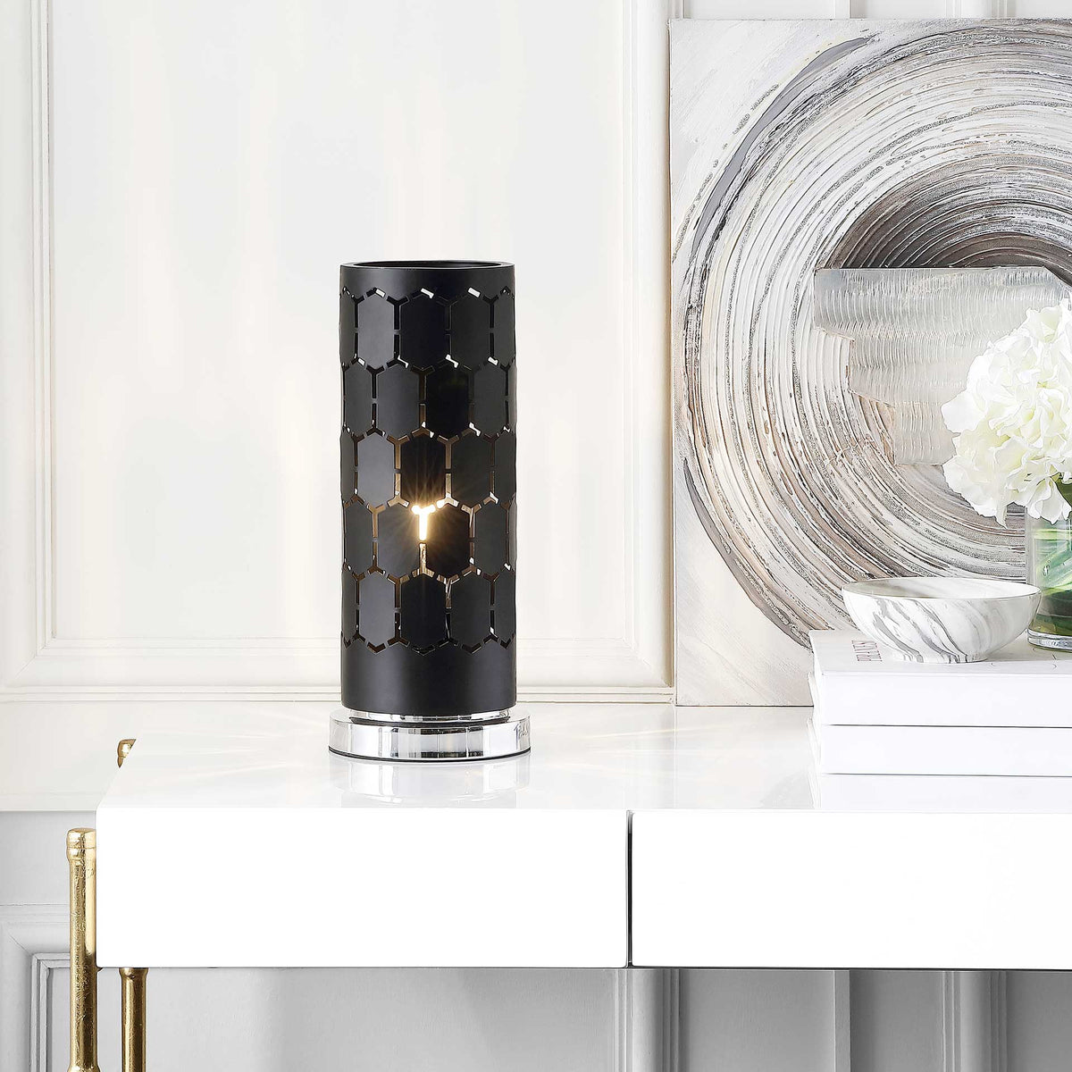 A warm glow shines through the black geometric shade, creating a striking tabletop accent