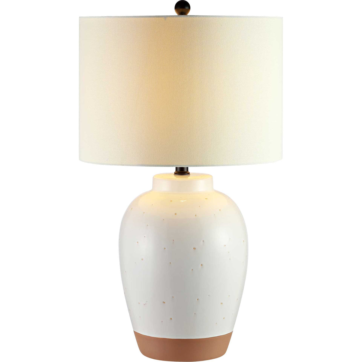 A warm glow shines through the white drum shade above a speckled ivory ceramic base