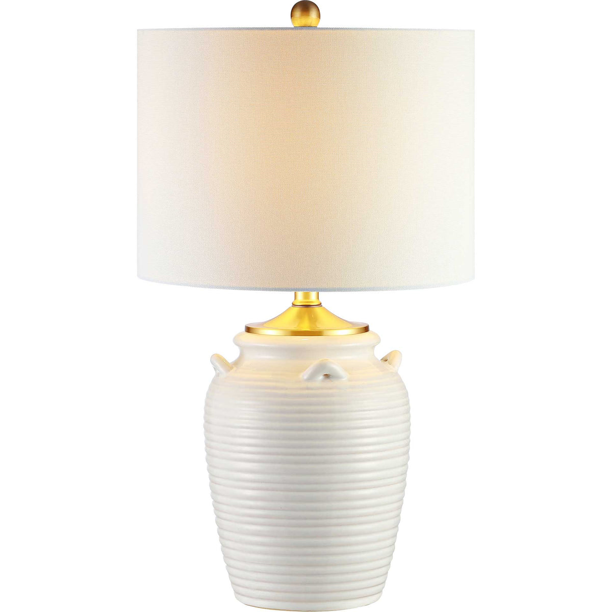 Warm light glows through the white drum shade above a ribbed ivory ceramic base with brass-tone details.