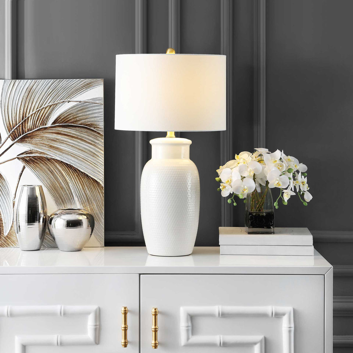 Soft light warms the white shade and highlights the ivory ceramic base and brass details.