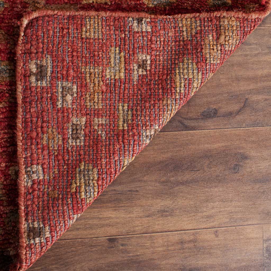 A folded corner reveals the rug's tightly woven backing in red, gold, and earthy neutrals