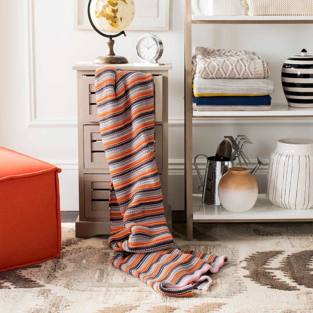 A draped cotton throw brings cozy orange, pink, and charcoal stripes to the room.