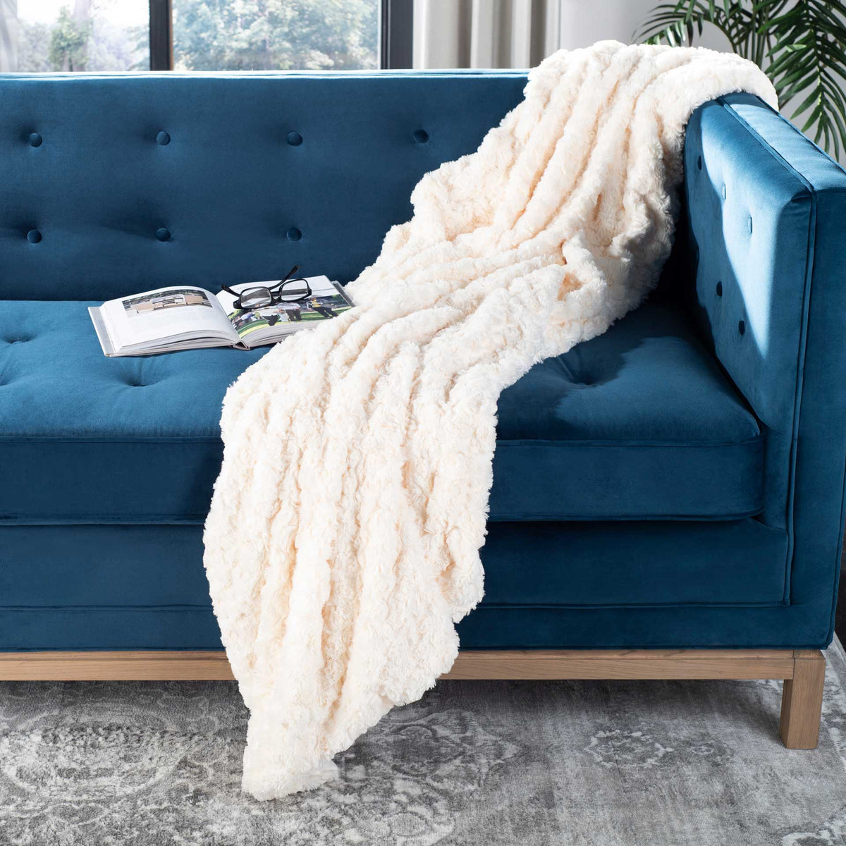 Cream faux fur throw drapes over a sofa in cozy folds, adding inviting texture and warmth