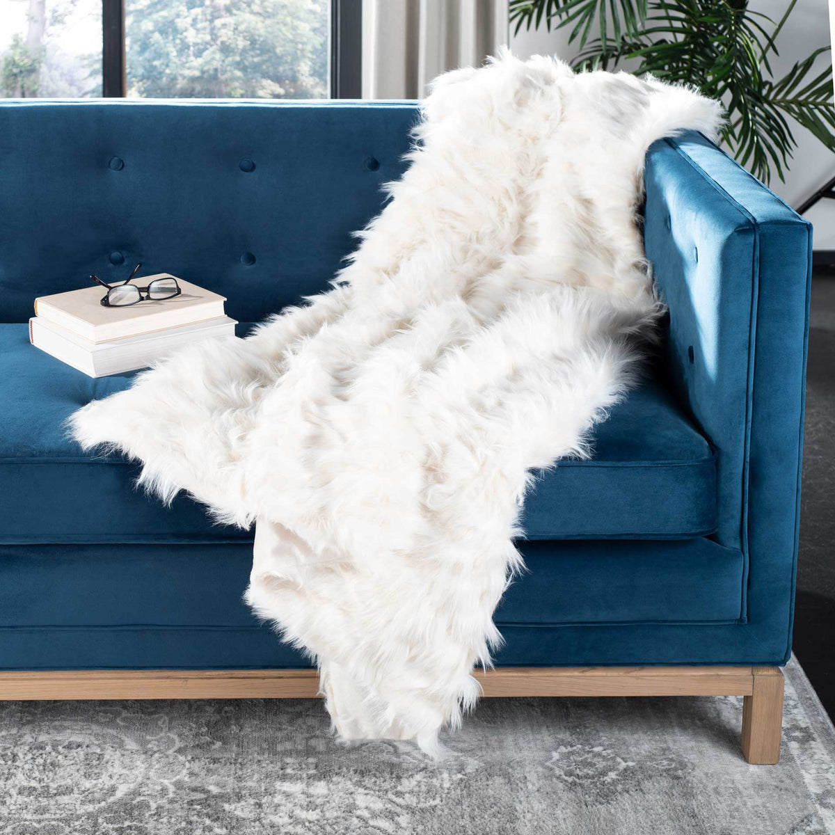 A fluffy white throw adds soft, feathery texture as it drapes over a blue sofa.