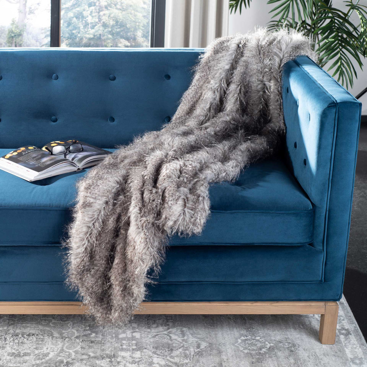 Long gray faux fur lends inviting texture to a blue sofa.