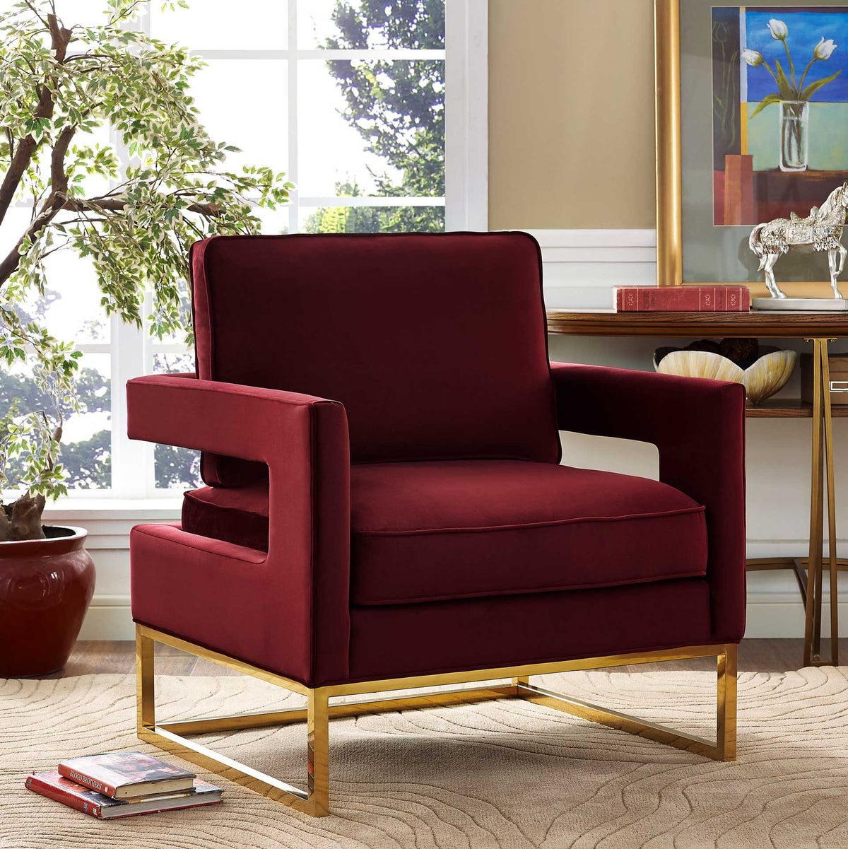 Maroon velvet, plush cushions, and an airy gold frame add a warm touch of glamour to a bright living room.