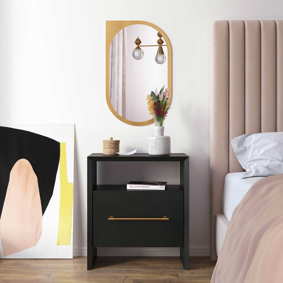A black nightstand with a gold pull adds contrast beside a softly upholstered bed