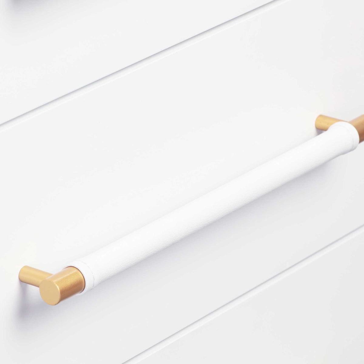 A white vegan leather-wrapped handle adds soft texture between warm brass ends