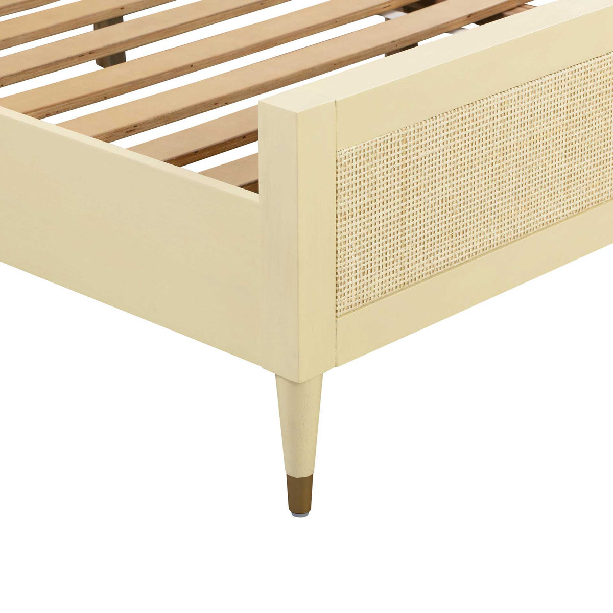 A tapered cream leg with a brass-tone cap adds a refined accent to the cane-paneled bed frame
