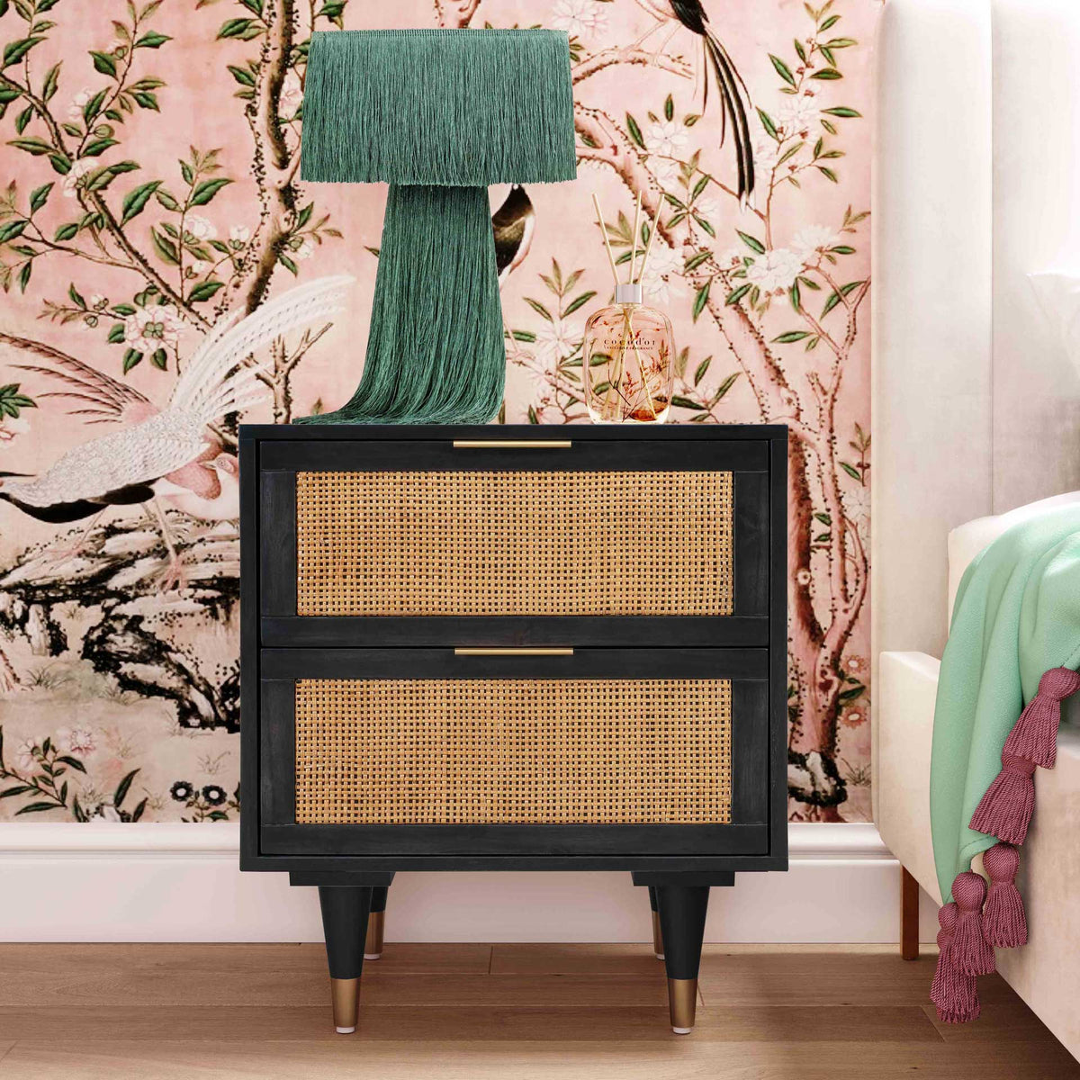 Natural cane and brass-tone accents add warmth to a black nightstand in a colorful, bohemian bedroom