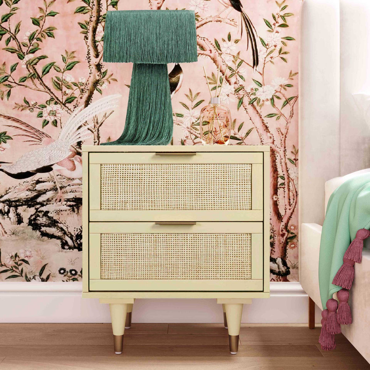 A cream cane-front nightstand adds soft color and natural texture to an eclectic, inviting bedside space