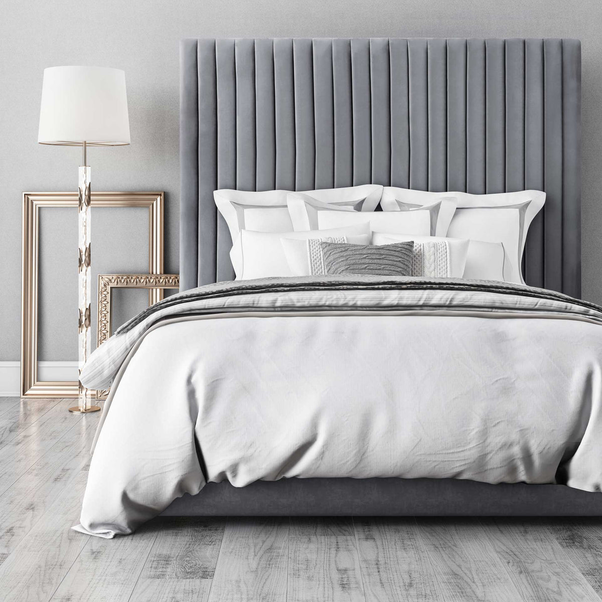 A lofty gray velvet headboard adds soft texture and bold vertical lines to a layered, neutral bed