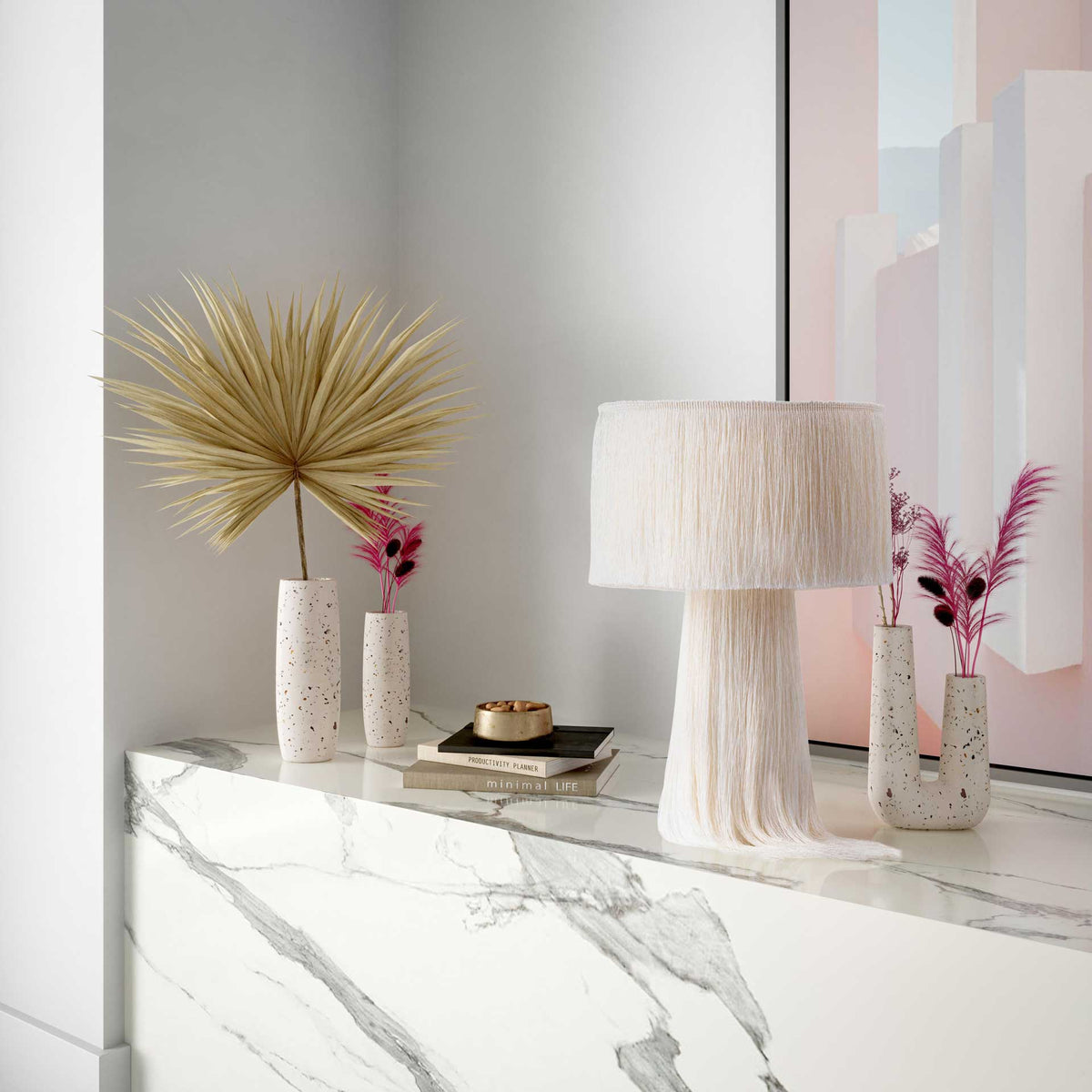 Slim white terrazzo vases complement dried palms and pink stems for a sculptural console accent