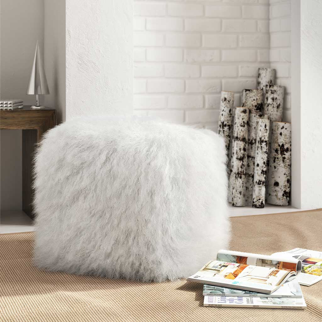 A white sheepskin pouf brings plush comfort and soft texture to a neutral living space