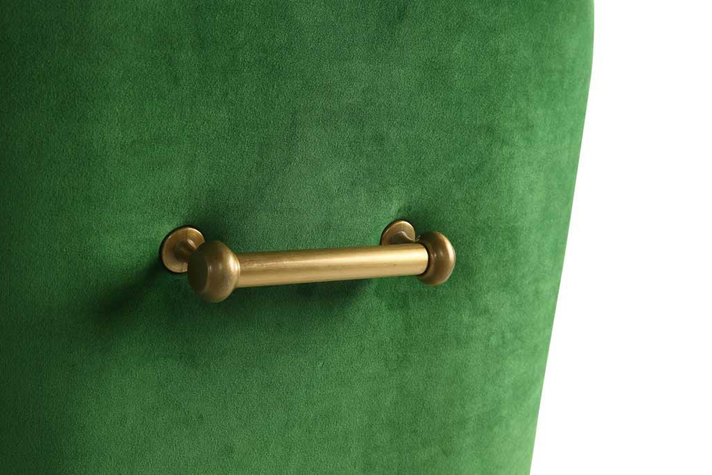 A rounded gold handle creates a striking contrast against the chair's lush green velvet upholstery.