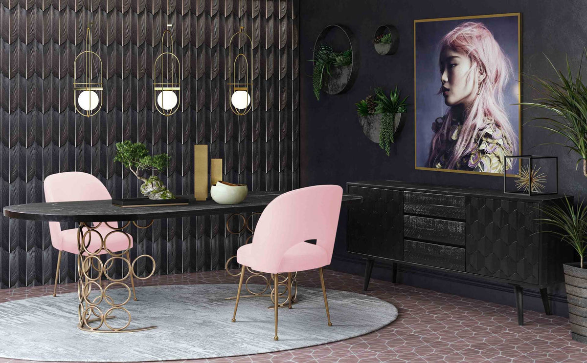 Blush pink velvet chairs and glimmering gold legs brighten a moody black dining room