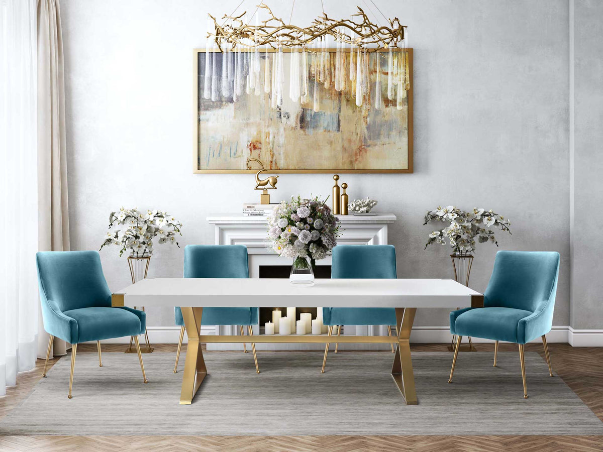 Sea blue velvet chairs bring soft color and elegant gold legs to a bright white dining table.
