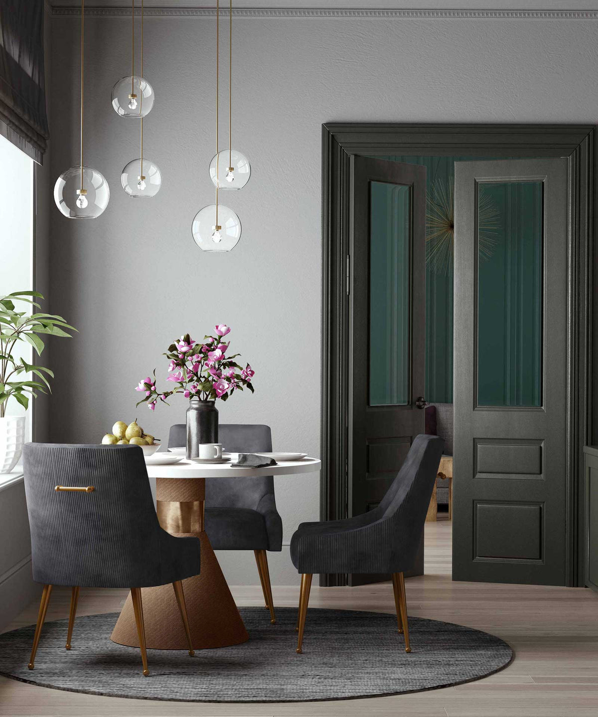 Pleated charcoal velvet chairs add depth and polished gold accents around a sculptural dining table.