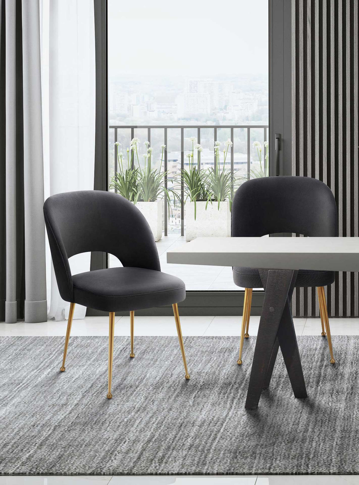 Dark gray velvet chairs add plush seating and gold accents beside a sunlit dining table