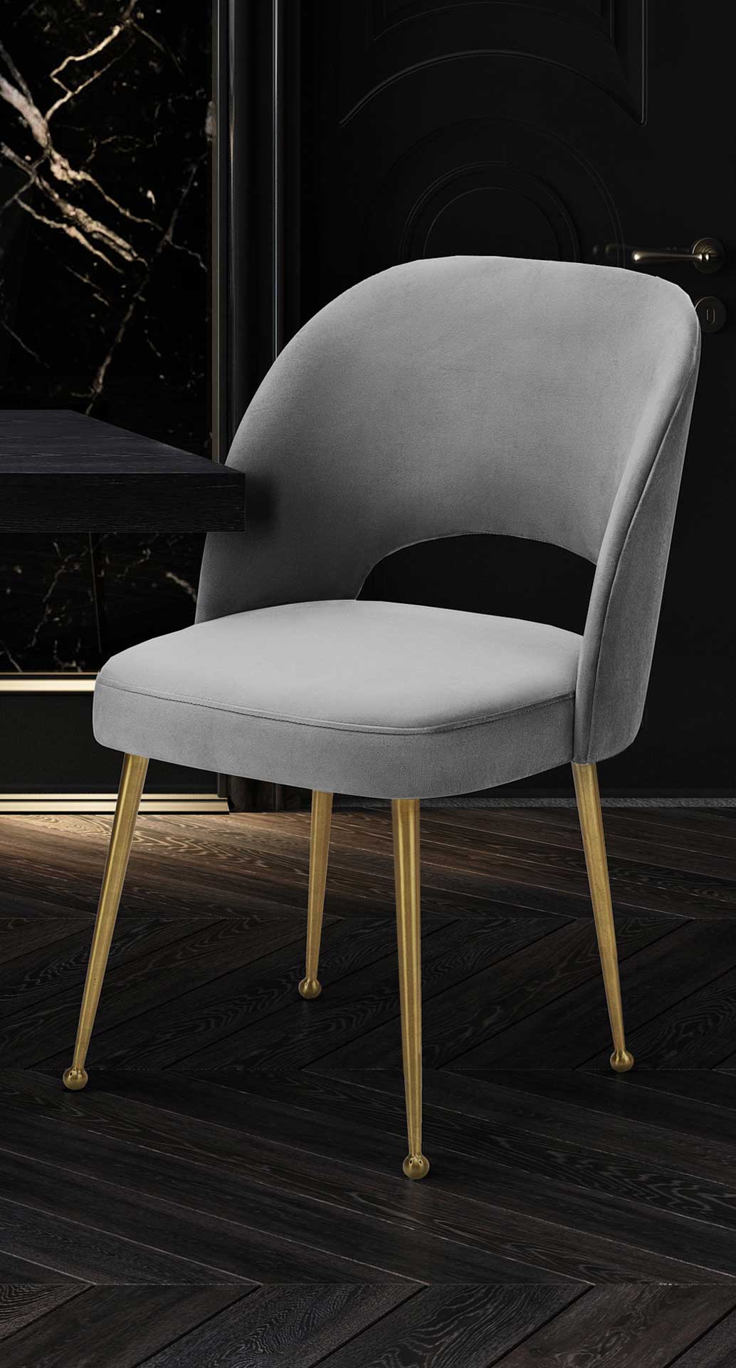 A plush light gray velvet chair brings gentle curves and warm gold legs to a dark dining nook