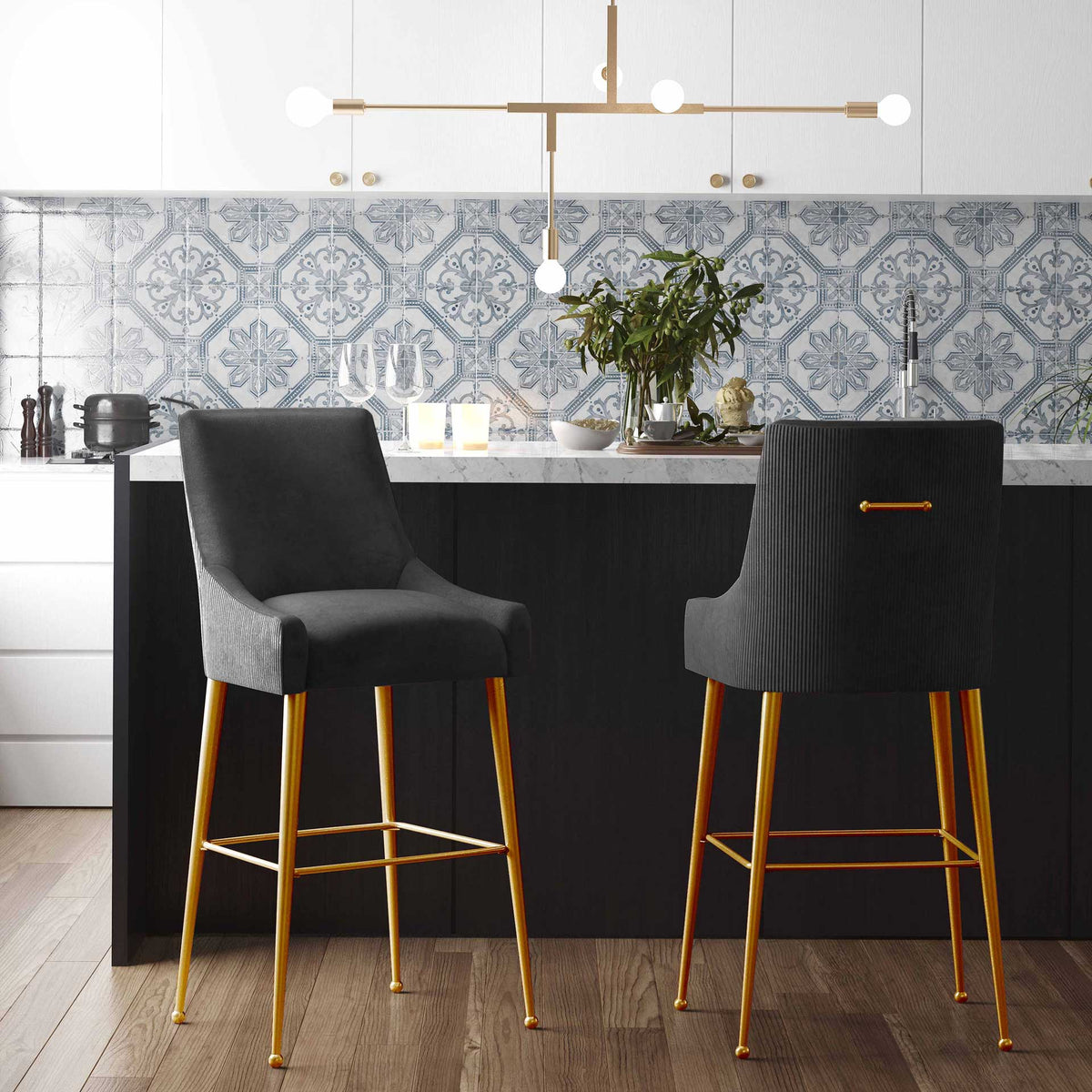 Pleated velvet bar stools with gold legs add a polished touch around a kitchen island