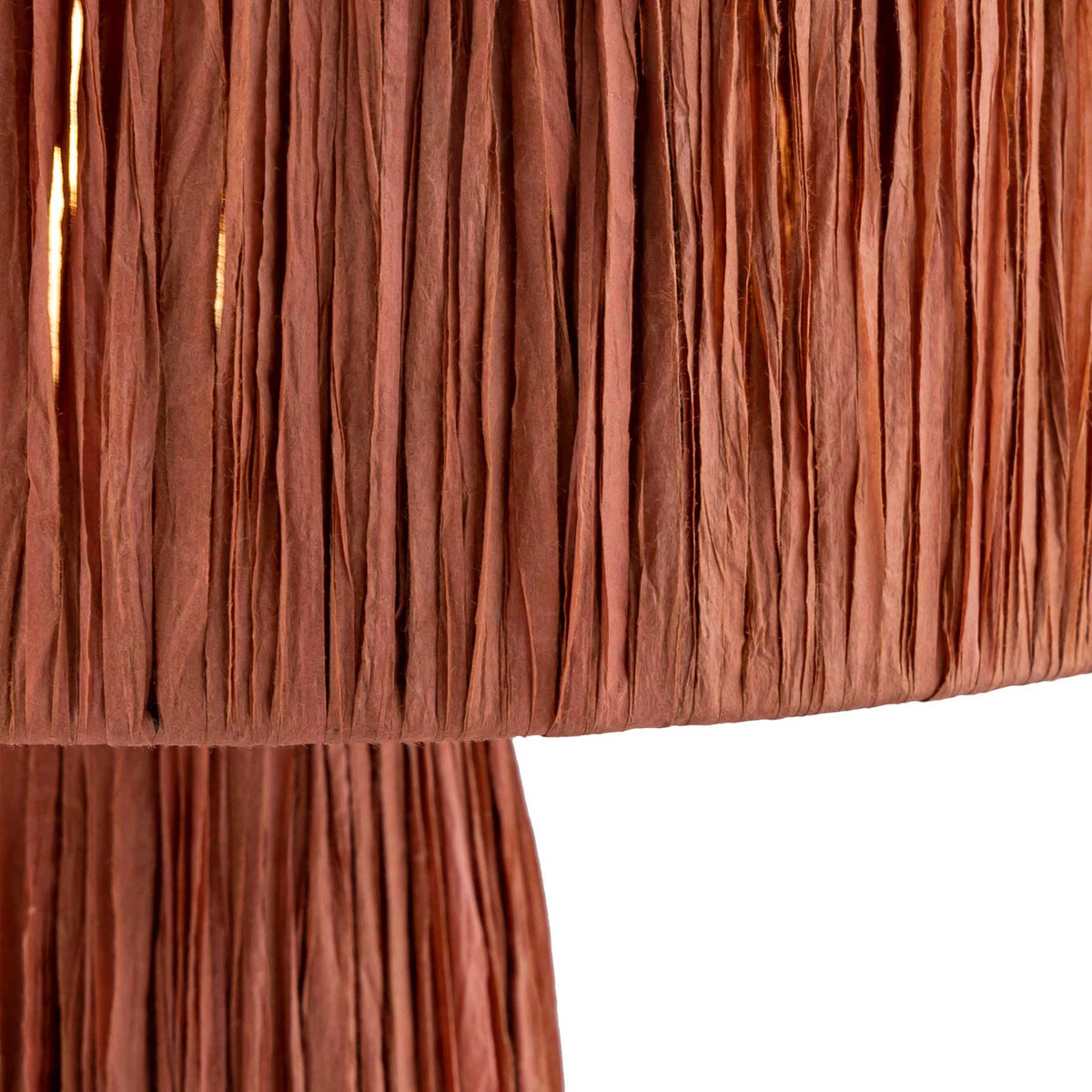 Crinkled brick-red raffia strands create a richly layered texture across the drum shade