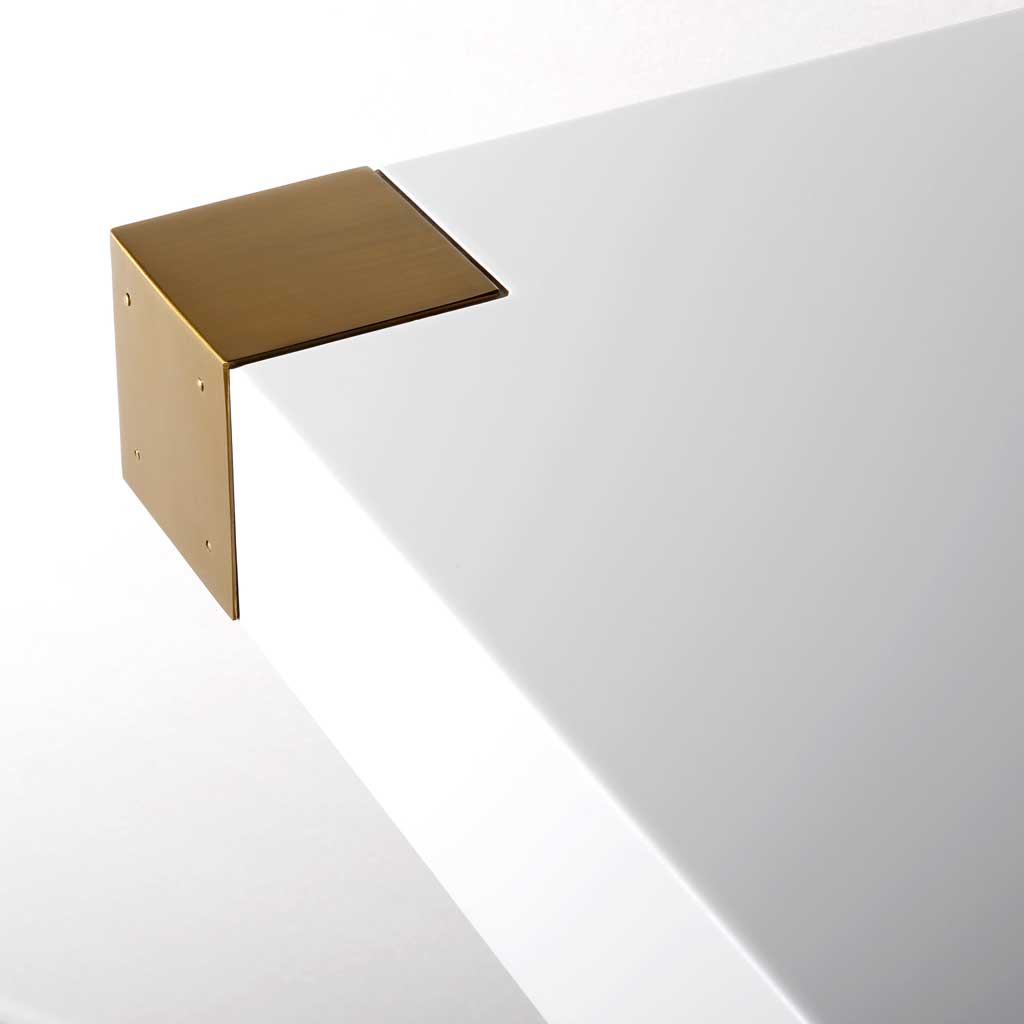 Brushed gold corner caps add a luxurious contrast to the smooth, high-gloss white tabletop.
