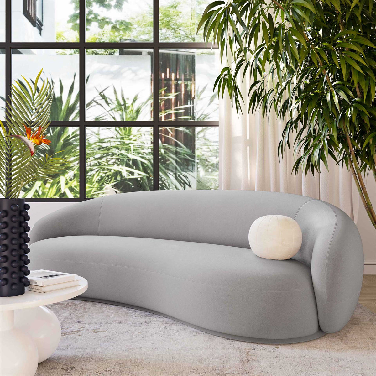 A light gray velvet sofa with enveloping curves creates a calm focal point for relaxed living