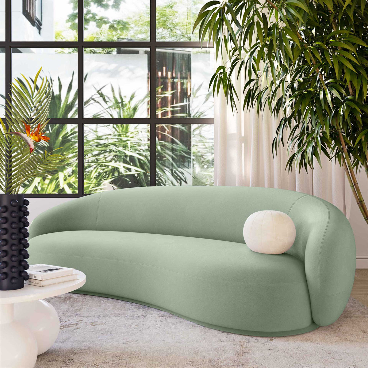 Soft moss green velvet and a sculptural curved silhouette bring a fresh, serene feel to this sofa