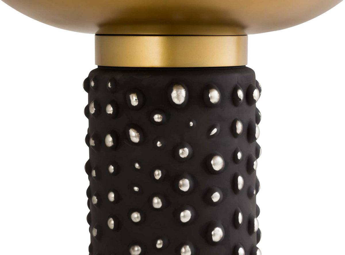 Reflective bubble details enliven the black glass pedestal beneath a warm brass collar.