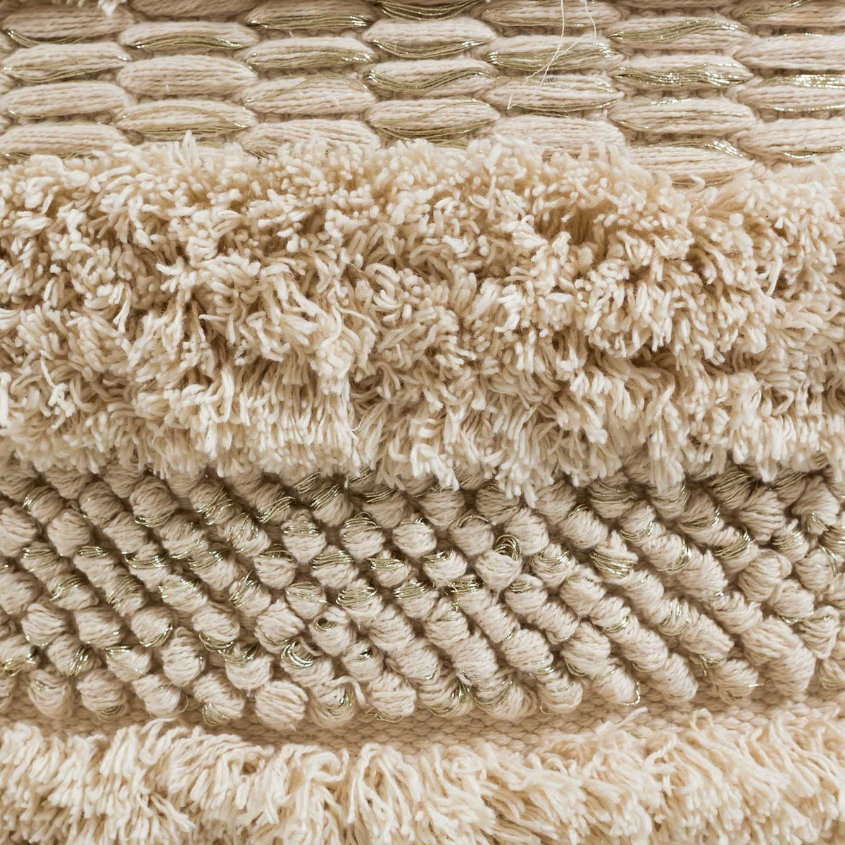 Soft cotton fringe, raised knots, and shimmering gold-tone threads create rich, tactile texture