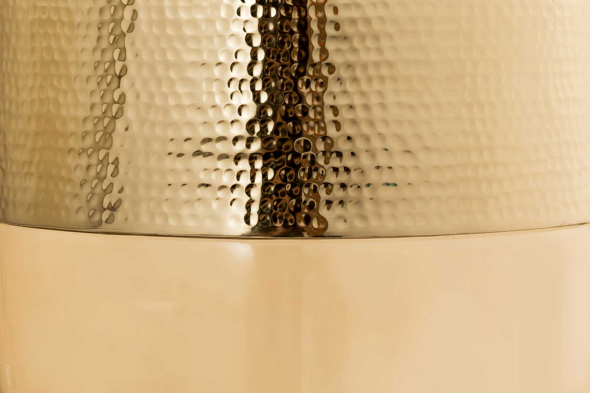 Hammered gold-finished metal meets smooth amber glass in a striking mix of texture and translucence.