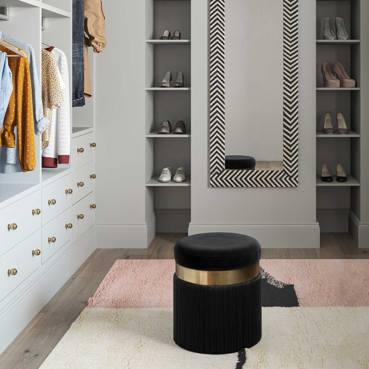 A compact black velvet ottoman brings soft seating and glamorous fringe to a dressing area