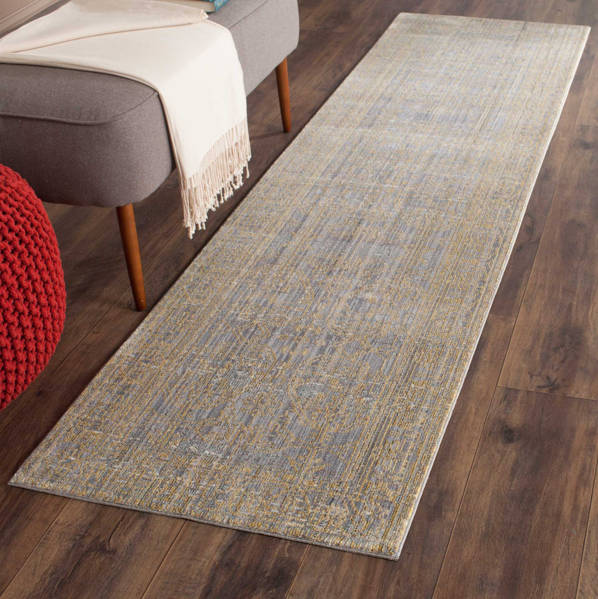 A gray and gold runner adds soft pattern beside upholstered seating on a dark wood floor