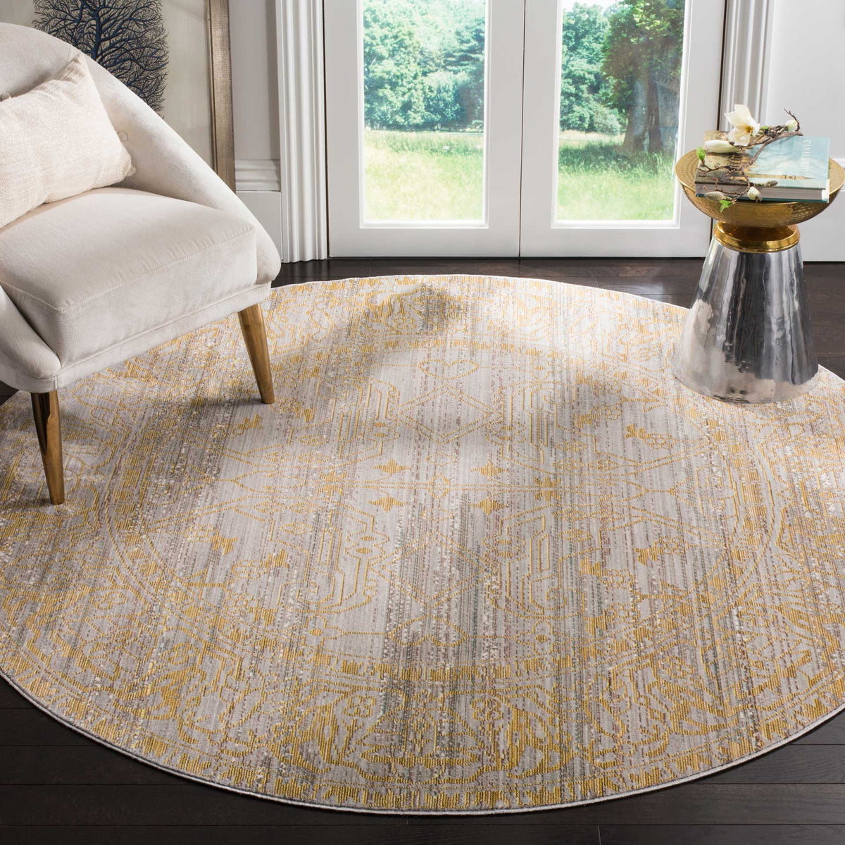 A gray and gold round rug adds softly distressed pattern to a bright seating area