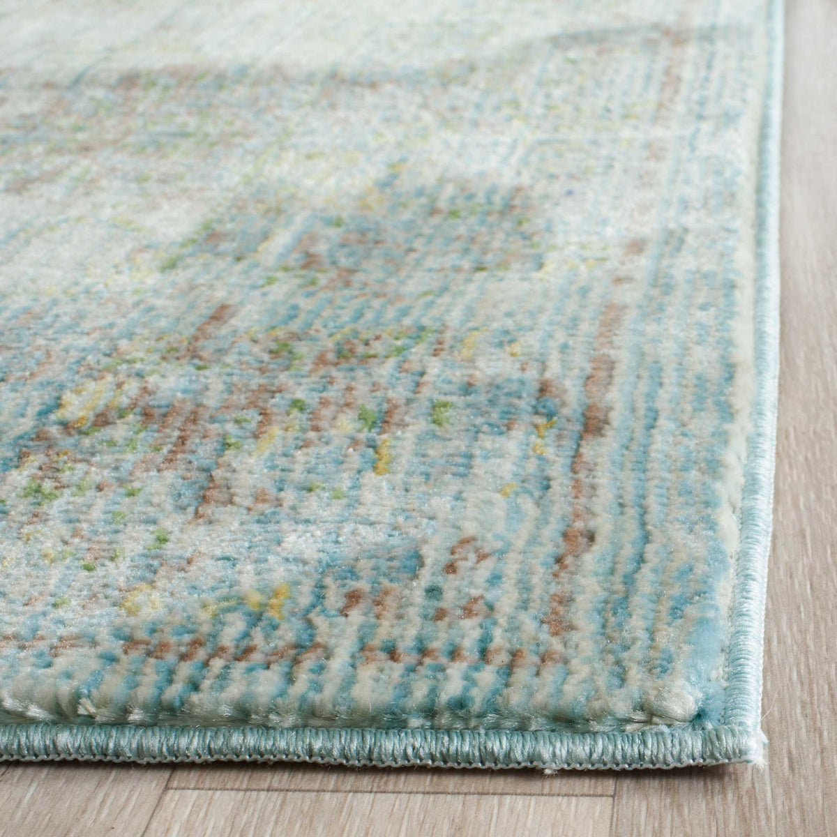 Soft blue, turquoise, and gold details meet a neatly bound edge on this low-pile rug