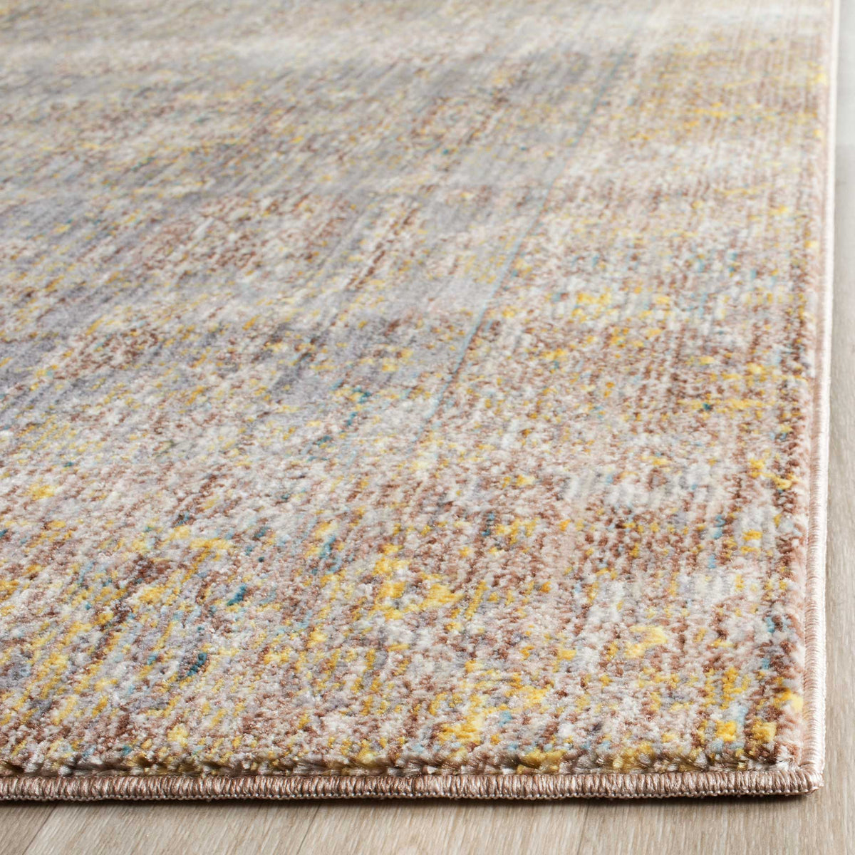 Tightly bound edges frame a softly textured pile in gray, gold, and muted blue tones.