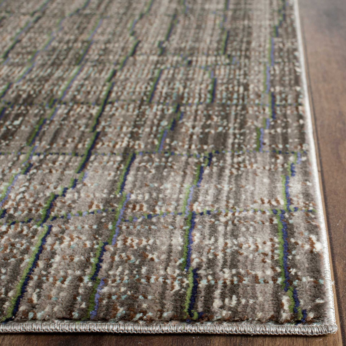 A neatly bound edge frames textured gray pile with blue, green, and warm brown streaks