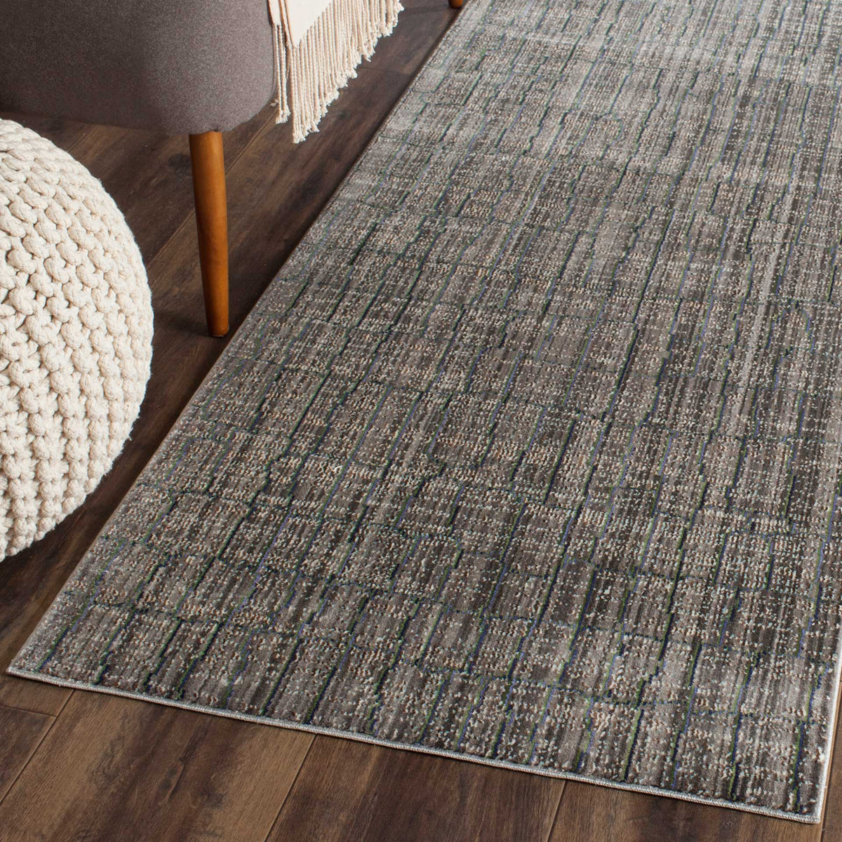 A gray abstract runner adds layered color and texture beside seating on a wood floor