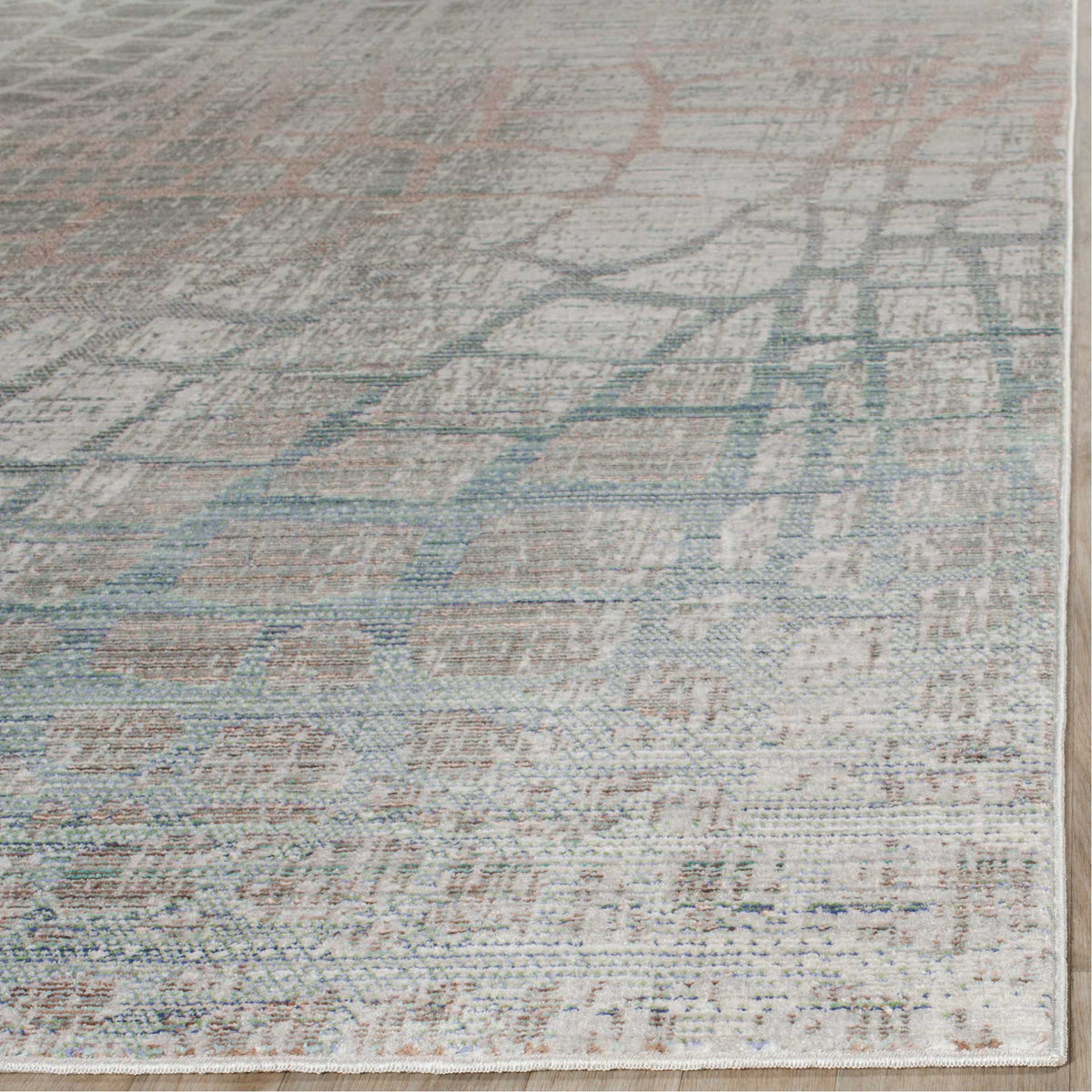Low-profile gray pile shows soft teal and blush patterning along a neatly bound corner.