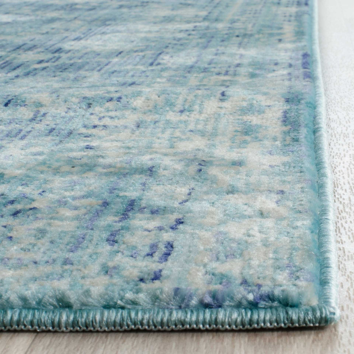 Soft blue and cream tones blend across the low-profile pile, finished with a neat bound edge