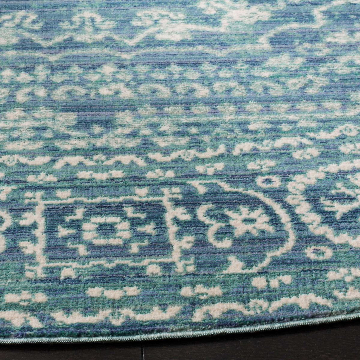 Layered blue and ivory motifs reveal textured pile and a neatly finished edge.